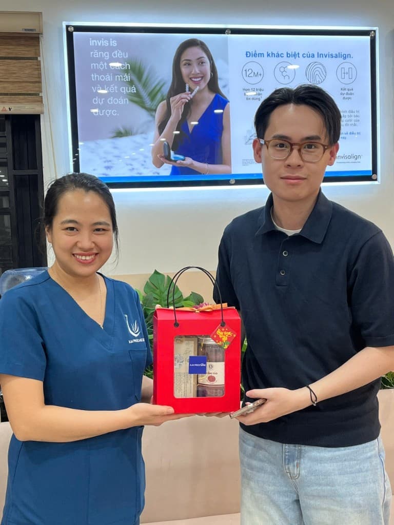 Clinician and patient holding a gift bag in front of an Invisalign display at the clinic