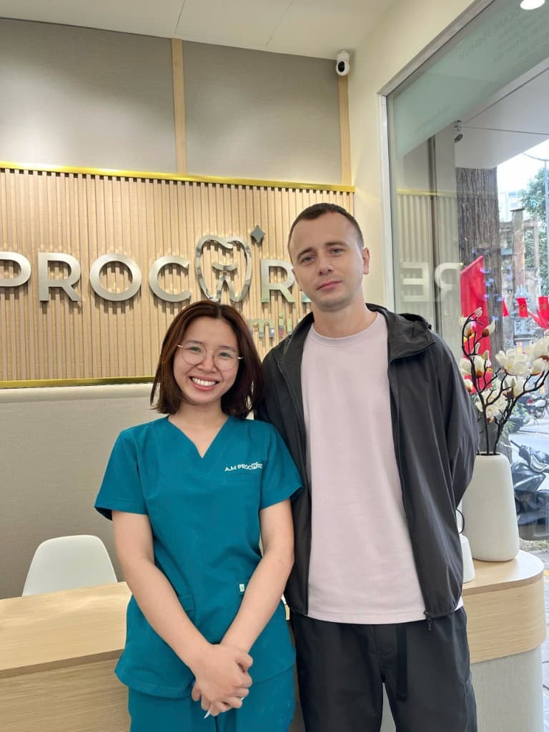 Dental team member and international guest smiling together at the clinic reception desk